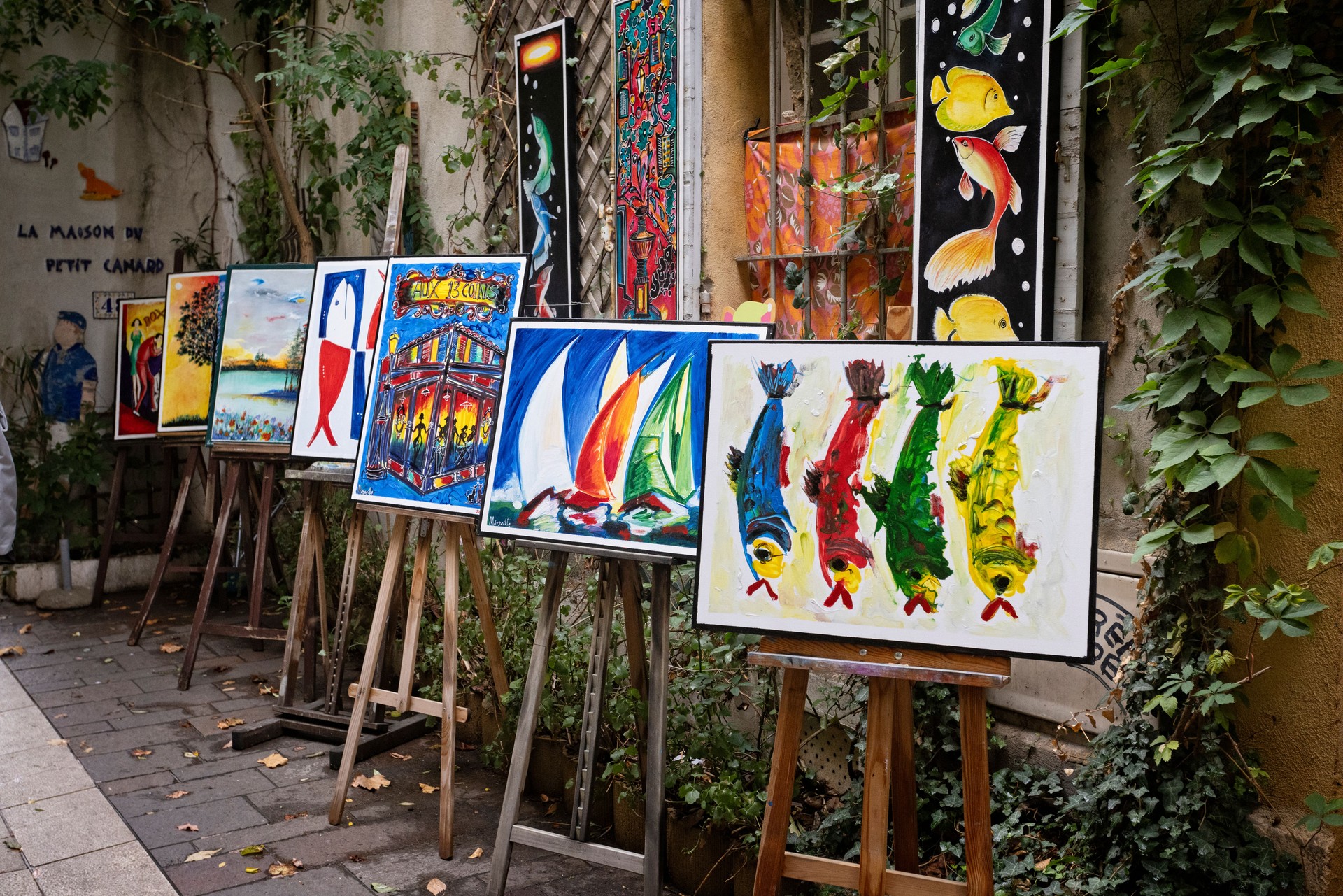 Colourful painitngs on display for sale in narrow streets of the medieval quarter of Marseille, France